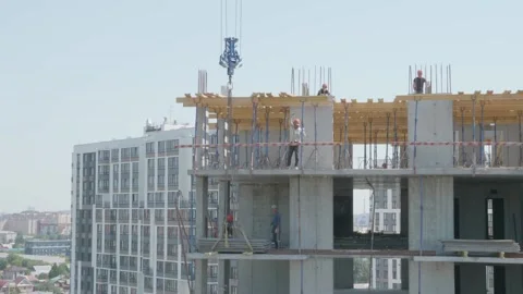 Crane transports building materials to construction site Stock Footage