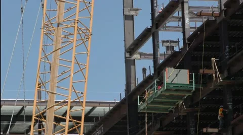 Crane with two loads of iron getting man handled by steel workers. Stock Footage 67557235