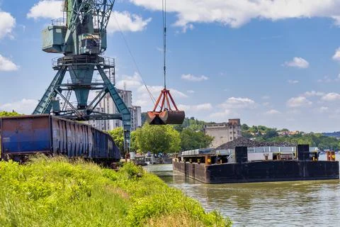 Crane unloading coal from barge to train wagon Stock Photos