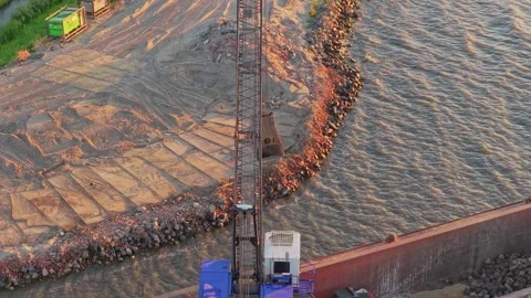 Crane unloading sand onto barge for dike reinforcement construction Vídeos de archivo 342809248