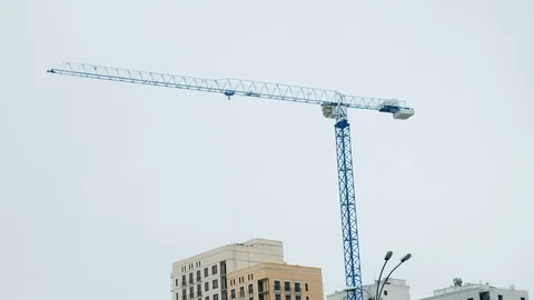 Crane Working on Construction Site Under Grey Cloudy Sky on a Rainy Day Stock Footage 119915091