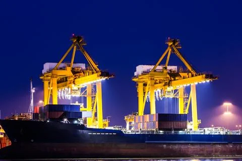 Crane working with container cargo in shipyard at dusk Stock Photos