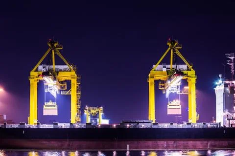 Crane working with container cargo in shipyard at dusk Stock Photos