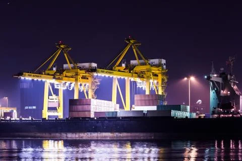 Crane working with container cargo in shipyard at dusk Stock Photos