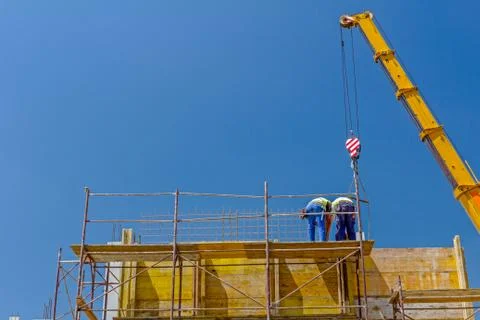 Crane is working with riggers, workers are assembly big mold for concreting Stock Photos