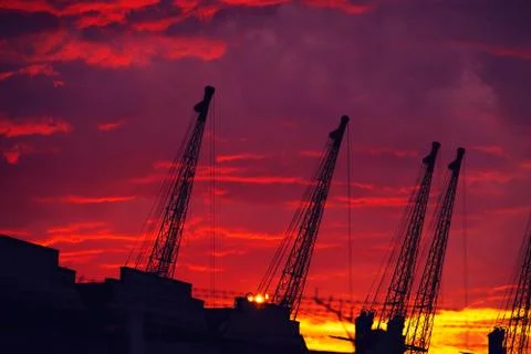 Cranes against dramatic sky at sunset. Stock Photos