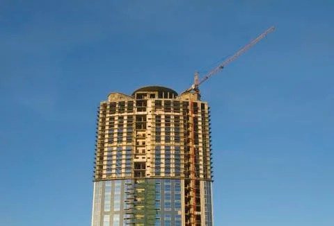 Cranes and building construction of a skyscraper early morning against the da Stock Photos
