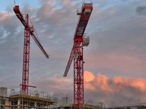 Cranes and building under construction on a sunset clouds background Stock Photos