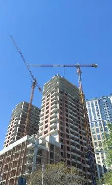 Cranes and construction of a high multi-storey building, house against the blue Stock Photos