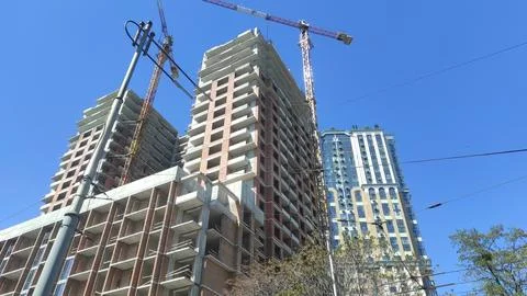Cranes and construction of a high multi-storey building, house against the blue Stock Photos
