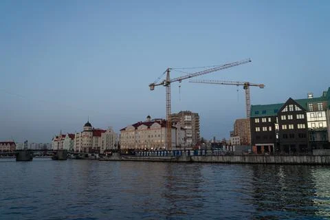 Cranes are being built on the river bank in an urban environment Stock Photos