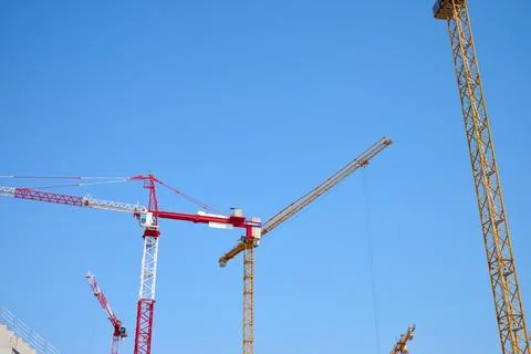 Cranes at a construction site with a clear blue sky. Stock Photos