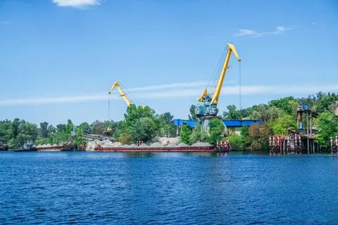 Cranes loading sand on a barge at quarry Stock Photos