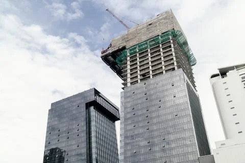 Cranes on top of under construction high-rise building Stock Photos