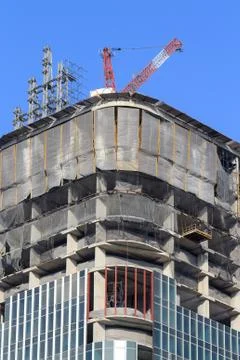 Cranes on top of under construction high-rise building Stock Photos