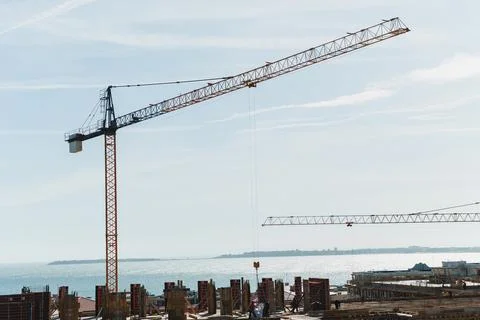 Cranes work at a construction site close to the water. Workers carry out task Stock Photos