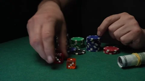 A craps player's hands roll two red dice onto a green table with colorful poker Stock Footage 332426745