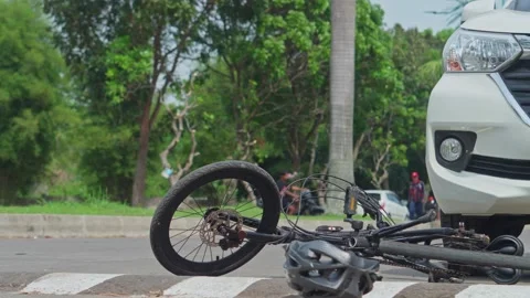 Crashed bicycle and helmet on road near white car illustrating traffic accident Stock Footage 336326888