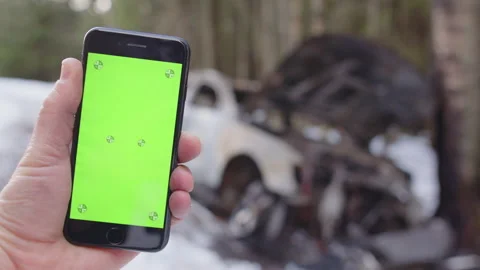 Crashed car on snowy road to hand holding cellphone with chroma key, focus shift Stock Footage 300427099