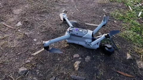 A crashed drone lies on the ground with a broken arm and a dislodged camera.. Stock Footage 296756575