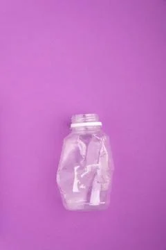 Crashed plastic bottle on blue purple background. Plastic utilisation concept Stock Photos