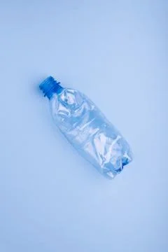 Crashed plastic bottle on bright blue background. Plastic utilisation concept Stock Photos