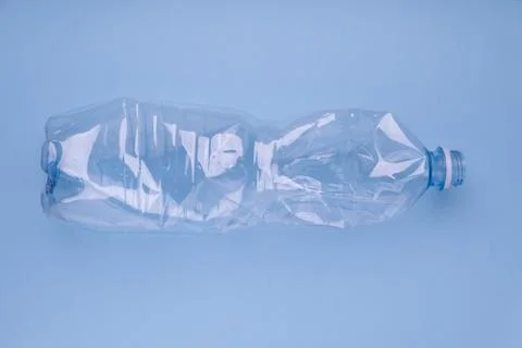 Crashed plastic bottle on bright blue background. Plastic utilisation concept Stock Photos
