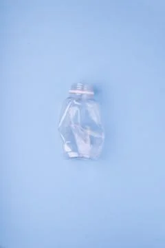 Crashed plastic bottle on bright blue background. Plastic utilisation concept Stock Photos