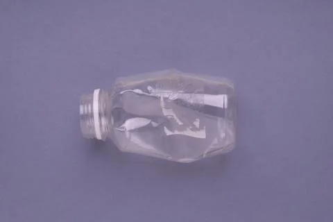 Crashed plastic bottle on gray background. Plastic utilisation concept Stock Photos