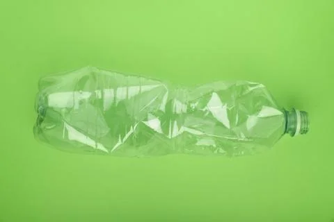 Crashed plastic bottle on green background. Plastic utilisation concept Stock Photos