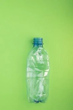 Crashed plastic bottle on green background. Plastic utilisation concept Stock Photos