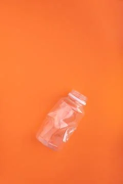 Crashed plastic bottle on orange background. Plastic utilisation concept Stock Photos
