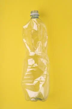 Crashed plastic bottle on yellow background. Plastic utilisation concept Foto stock