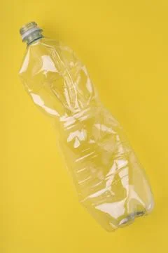 Crashed plastic bottle on yellow background. Plastic utilisation concept Stock Photos
