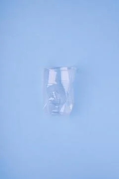 Crashed plastic cup on blue background. Plastic utilisation concept. Ecological Stock Photos