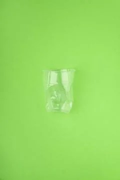 Crashed plastic cup on green background. Plastic utilisation concept. Ecological Stock Photos