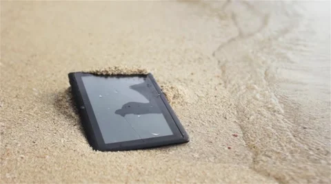 Crashed tablet is washed by the waves on the beach Stock Footage 57055205
