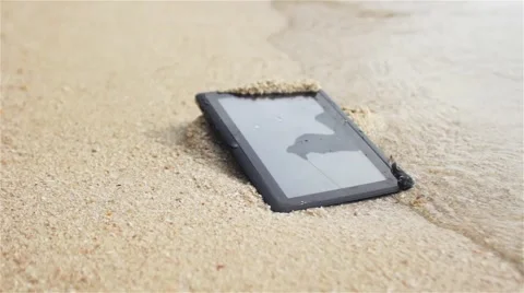 Crashed tablet is washed by the waves on the beach Stock Footage 57063081