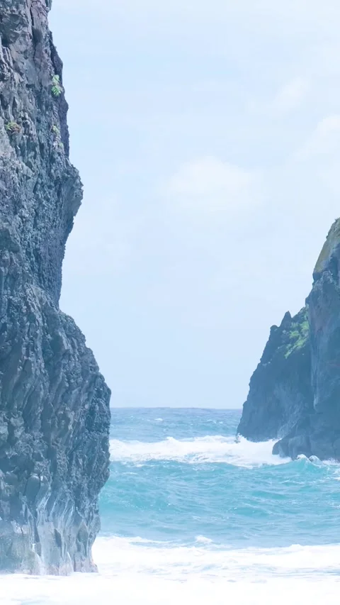 Crashing ocean waves passing through dramatic rocky cliffs 库存影片 334440002