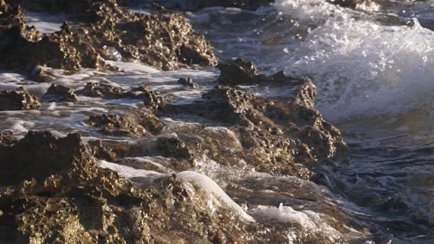 Crashing ocean waves splash against jagged rocks on the shoreline. Stock Footage 337408741
