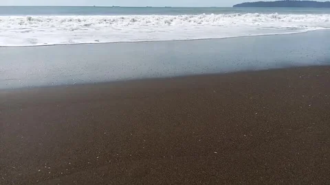 The crashing waves of the beach, and next to it is the island of Nusakambangan,  Stock Footage 299807747