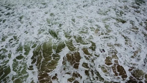 Crashing waves create a foamy texture on the shore, showcasing the oceans Stock Footage 317658257