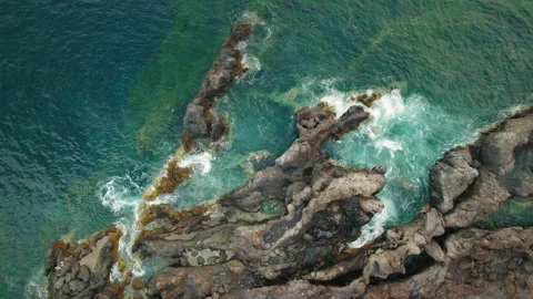 Crashing waves meet volcanic cliffs, forming pools in intricate coastal geology Stock Footage 289475415