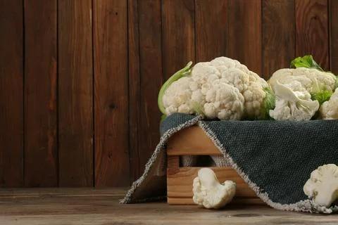 Crate with cut and whole cauliflowers on wooden table. Space for text Stock Photos