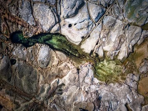 Cratered patterns on ocean rockshelf Stock Photos