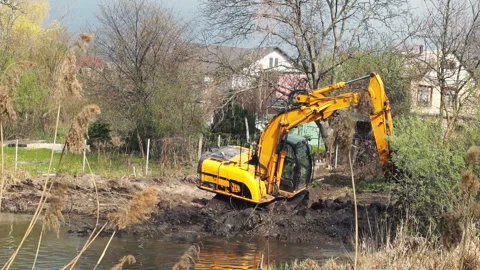 Crawler excavator or digger dredges on the lake Stock Footage 128654960