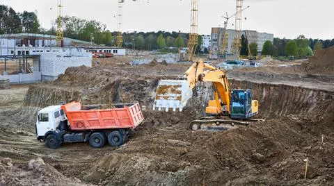 Crawler excavator in process of loading sand and soil to multi-ton mining truck Stock Photos