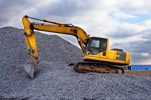 Crawler excavator in the rays of the setting sun at sunset digs earth and san Stock Photos