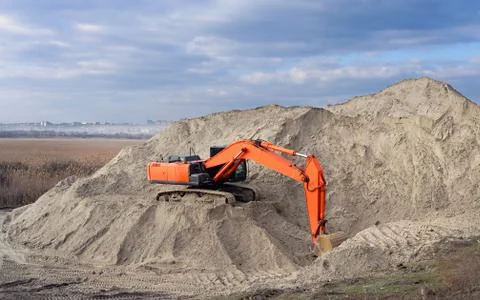 Crawler excavator in the rays of the setting sun at sunset digs earth and san Stock Photos