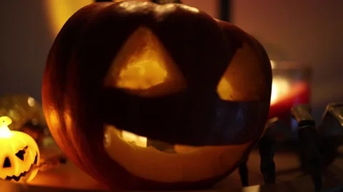 Crawling skeleton hand approaches glowing jack o lantern beside a candle Video stock 346147367